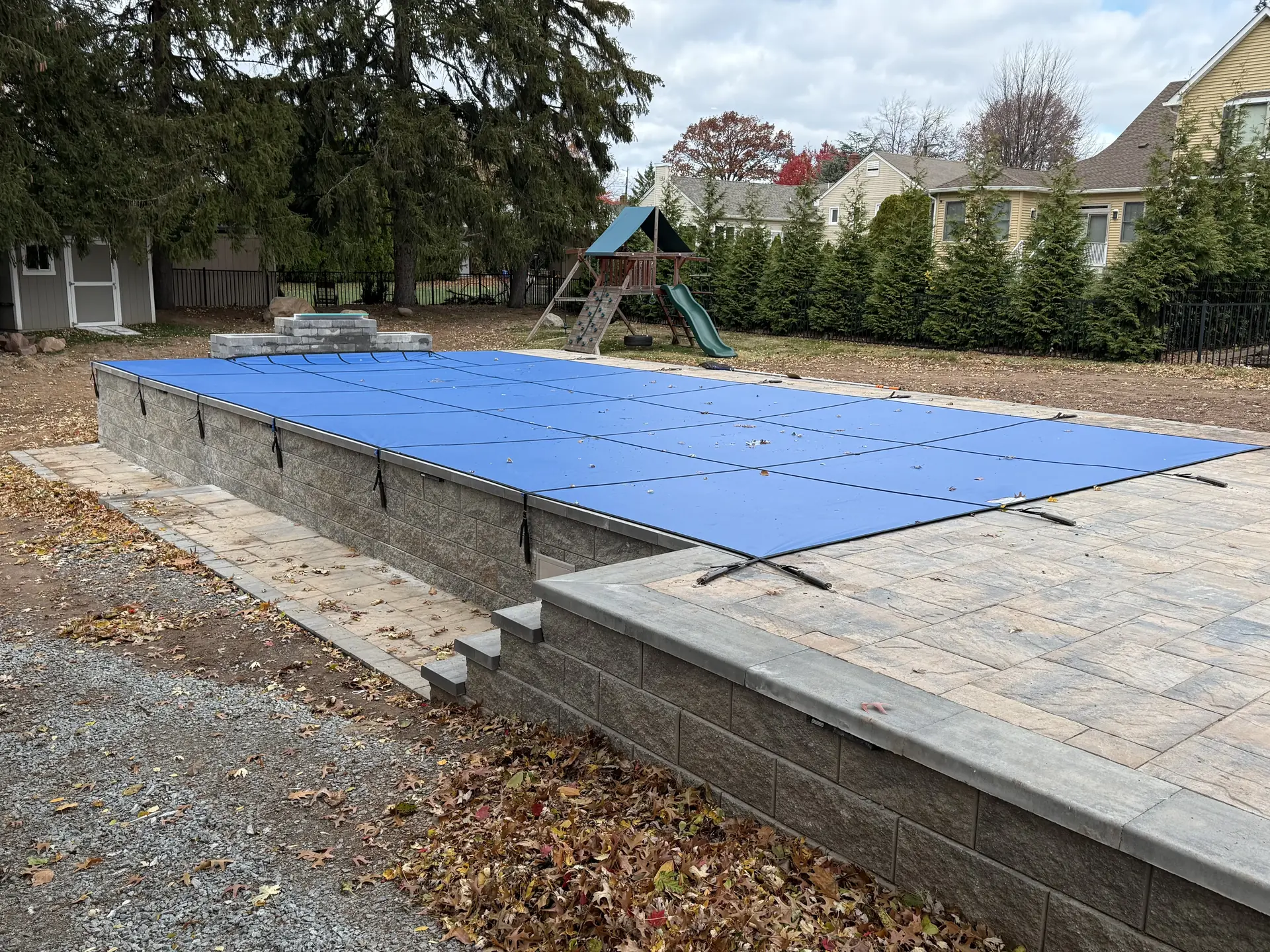 Inground pool closed, mature trees in background